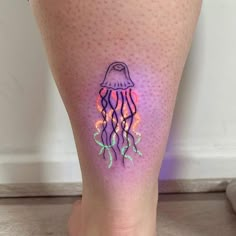 a woman's leg with a jellyfish tattoo on it, while the image is lit up