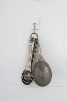 two measuring spoons hanging from hooks on a wall