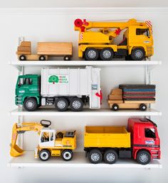 toy trucks and construction vehicles are lined up on white shelves in a playroom or bedroom