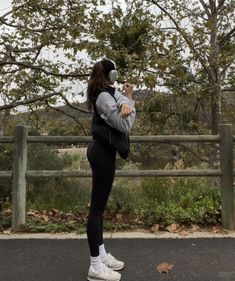 a woman is standing in the street with her back to the camera and wearing headphones