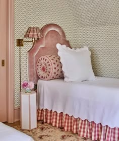 a bedroom with two twin beds and a pink headboard on the wall next to each other