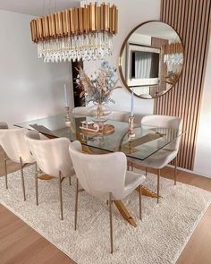 a dining room table with white chairs and a round mirror