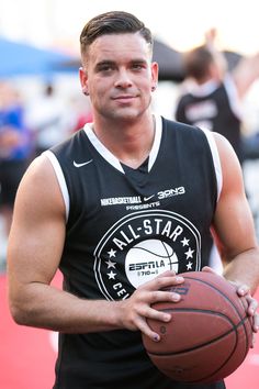 a man holding a basketball on top of a red carpeted court with other people in the background