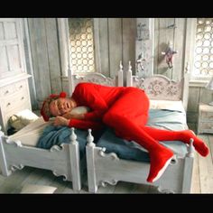 a man in red pajamas laying on top of a white bed