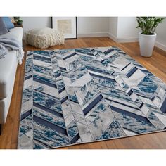 a blue and white area rug with an abstract design on the floor in front of a couch