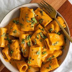 a white bowl filled with pasta covered in sauce and garnished with parsley