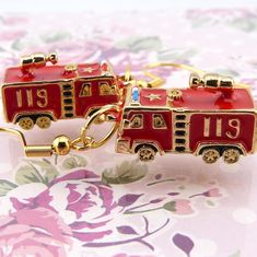 two red firetruck shaped earrings with gold trimmings and numbers on them