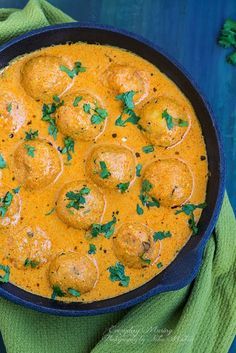 a pan filled with meatballs and sauce on top of a green towel