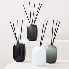 three black and white vases with sticks sticking out of them sitting on a table