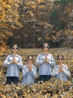 four people standing in the middle of a field with their hands together and wearing sunglasses