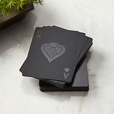 four black playing cards sitting on top of a white table next to a potted plant