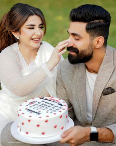 a man and woman sitting next to each other with a cake in front of them