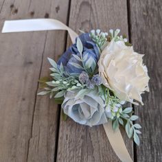 a boutonniere with flowers and greenery on a wooden surface, ready to be used as a corsage