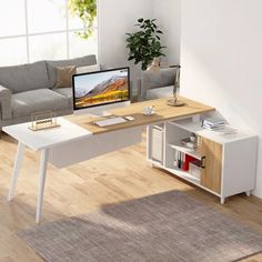 a living room with a couch, coffee table and computer monitor on the corner desk