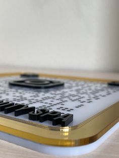 a close up of a remote control on a wooden table with white and black letters