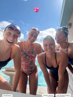 three women in bathing suits and goggles are smiling at the camera while standing next to a swimming pool