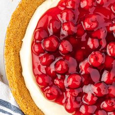 a cheesecake topped with cherries on top of a blue and white striped napkin