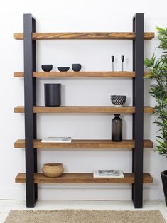 a wooden shelf filled with black vases and other decorative items on top of it