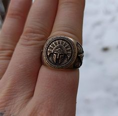 a person's hand with a ring on it that has an image of a cross in the middle