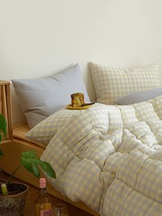 a bed with yellow and white checkered comforter next to a potted plant