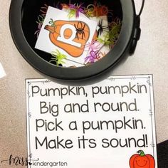 a black bowl filled with pumpkins next to a sign that says pumpkin, pumpkin big and round pick a pumpkin make it's sound