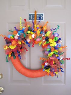 an orange wreath with colorful streamers on the front door