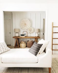 a living room with a white couch and some pillows on the floor next to a table