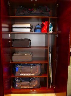 an open wooden cabinet filled with lots of luggage