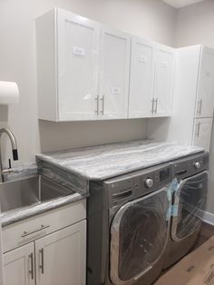 a washer and dryer in a room with white cupboards on the walls