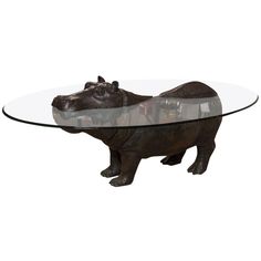 a glass table with a rhinoceros on it's legs and a bear figurine underneath