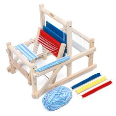 a wooden weaving machine with three different colors of yarn next to it on a white background