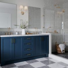 a bathroom with two sinks and blue cabinets in the shower area, along with a checkered tile floor