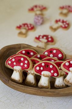 cookies decorated with red and white mushrooms on a wooden plate