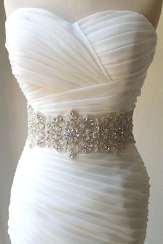 a white wedding dress with crystal beading on the waist