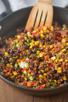 a skillet filled with taco salad and a wooden spatula on the side