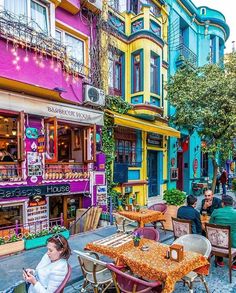 people sitting at tables in front of colorful buildings