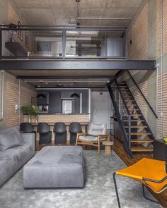 a living room filled with furniture and a stair case in front of a brick wall