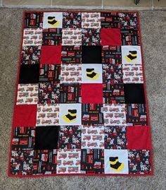 a red and black quilted blanket on the floor