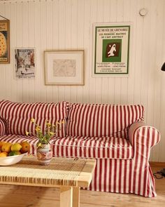 a red and white striped couch sitting in a living room next to a wooden table