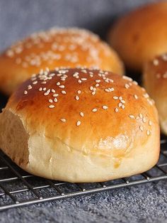 three buns with sesame seeds sit on a cooling rack