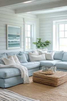 Perfect for a coastal-inspired home, this blue couch living room design utilizes a soft blue sofa reminiscent of the sea to anchor a nautical theme. Complementary decor includes white and navy striped cushions, a jute rug, and decorative elements like a model sailboat or ocean-themed artwork. Light, airy curtains allow natural light to enhance the bright, open feel of the space. The overall effect is one of calm and casual seaside living. Click here to see more nautical-themed blue couch livi... Coastal Cushions Couch, Bright Coastal Interior Design, Coastal Living Rooms Blue Sofa, Light Blue Decor Living Room, Living Room Inspiration Coastal, Beach House Couch, Blue Curtains Living Room Ideas, Coastal Sectional, Beach House Interior Living Room