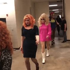 three women dressed in pink and black are walking down the hallway with long red hair