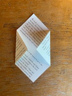 an origami piece of paper with some type of text on it sitting on top of a wooden table