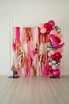 pink, silver and gold balloons are on display in front of a wall with an arch