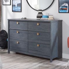 a bedroom with a dresser, mirror and pictures on the wall