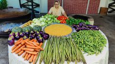 a woman sitting in front of a table filled with vegetables