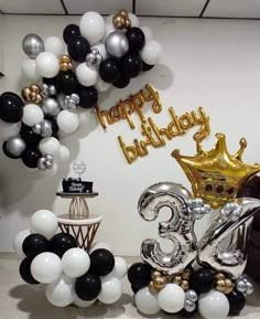 a birthday party with balloons and black, white, and gold decorations in the shape of a crown