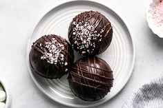 three chocolate covered donuts on a plate with sprinkles next to it