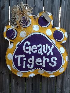 a yellow and purple sign that says geaux tigers on it's side next to a fence