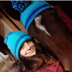 a woman in a blue hat is next to a brown horse